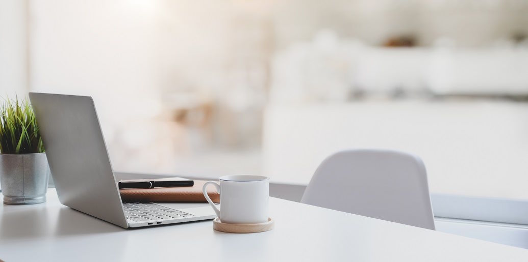Schreibtisch mit Laptop und Tasse auf Untersetzer